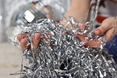 Photo of Woman with silver tinsel on floor indoors, closeup