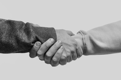 Image of Help and support. People holding hands on light grey background, closeup. Toned in black and white