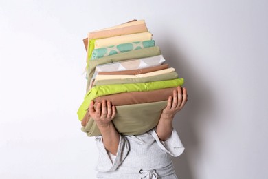 Woman holding stack of clean bed linens on white background