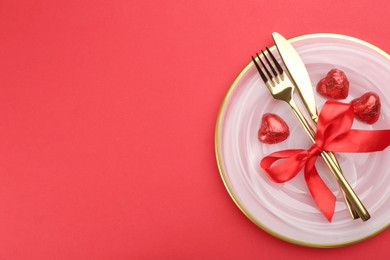 Beautiful table setting on red background, top view with space for text. Valentine's Day dinner