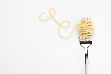 Photo of Fork with tasty pasta on white background, top view. Space for text