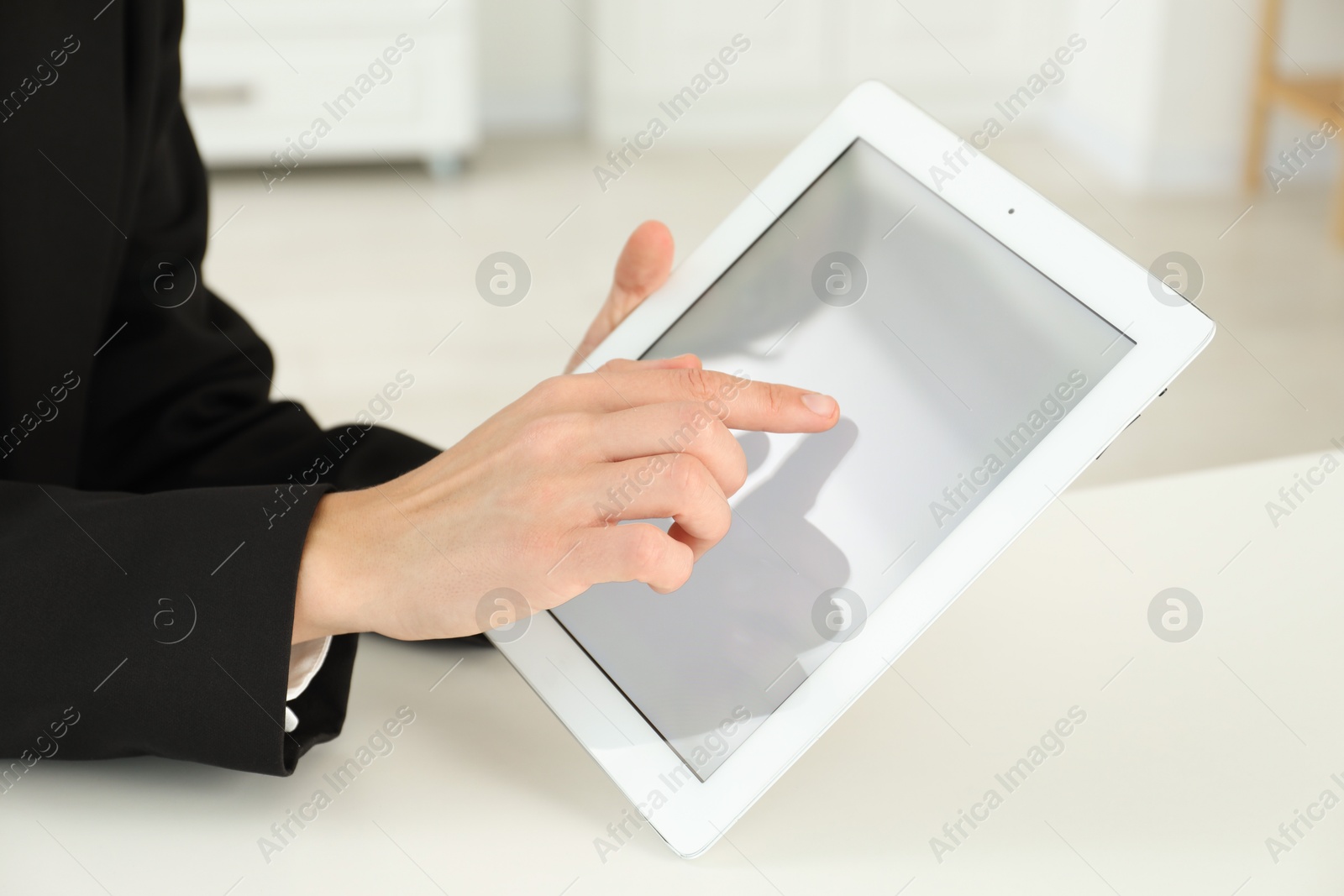 Photo of Businesswoman using tablet at white table indoors, closeup. Modern technology