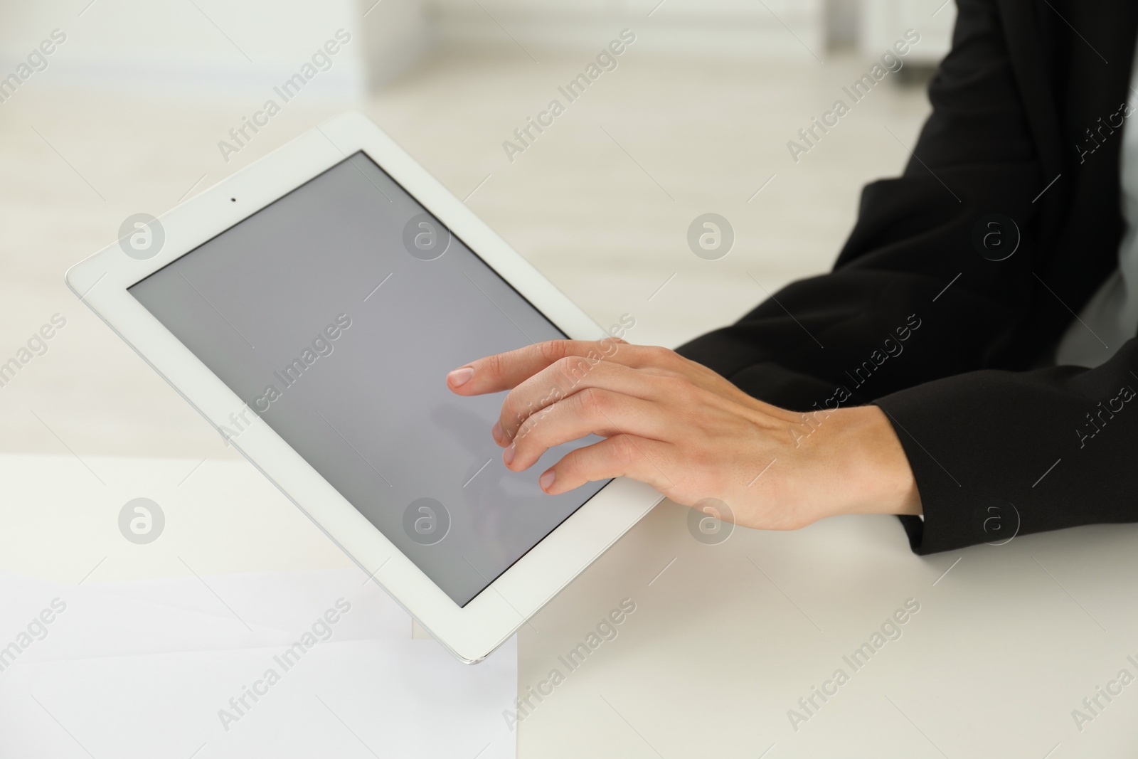 Photo of Businesswoman using tablet at white table indoors, closeup. Modern technology