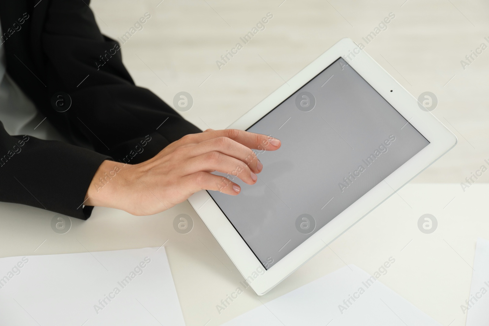 Photo of Businesswoman using tablet at white table indoors, closeup. Modern technology