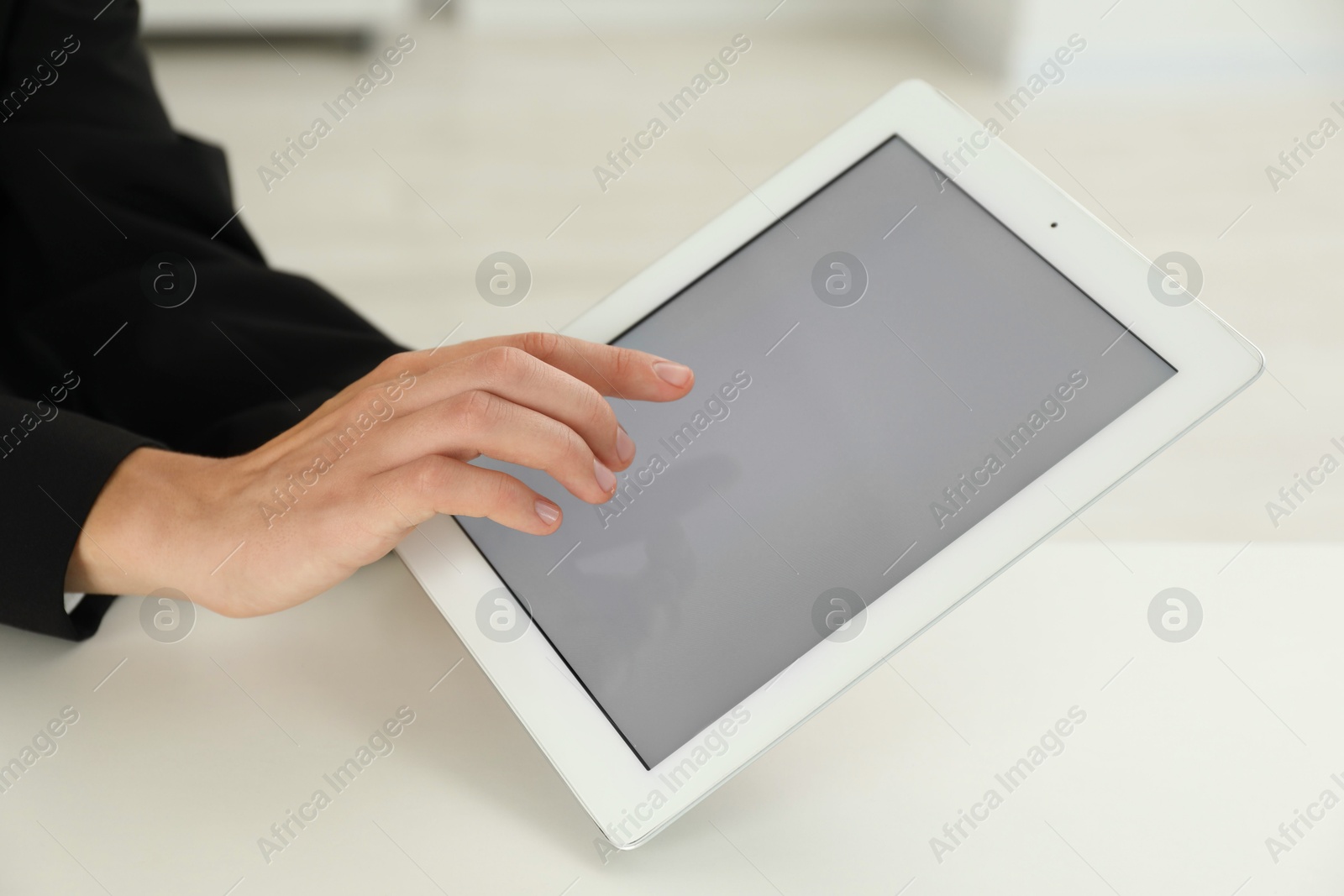 Photo of Businesswoman using tablet at white table indoors, closeup. Modern technology