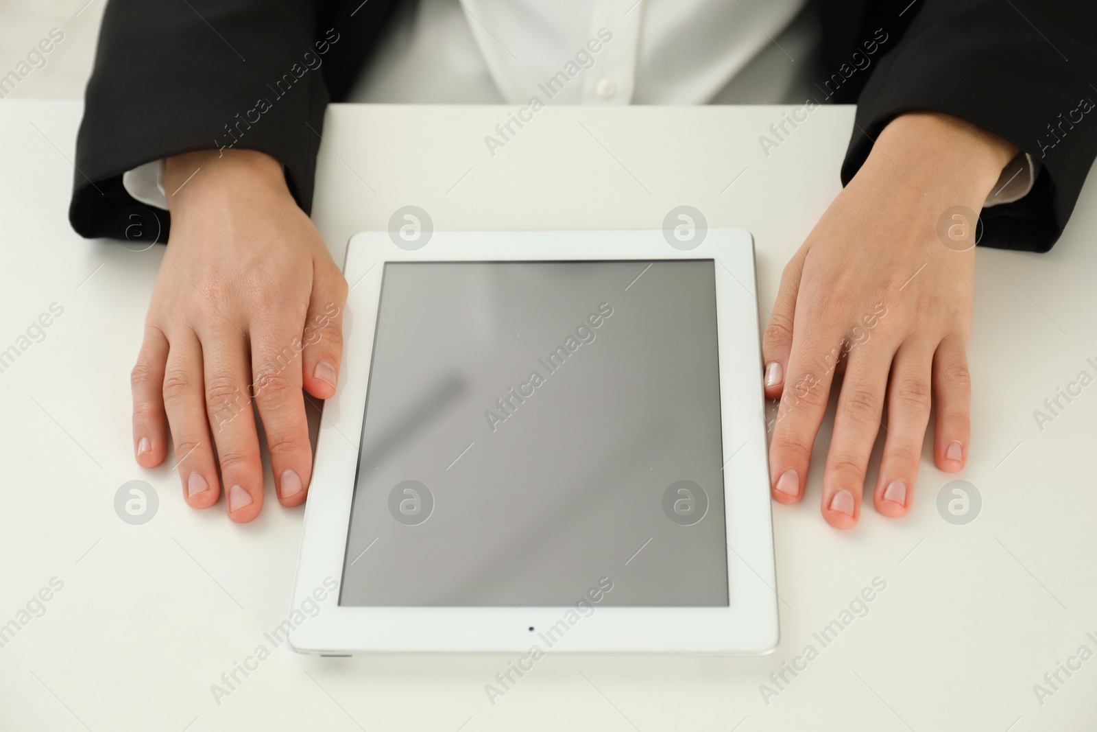 Photo of Businesswoman with tablet at white table indoors, closeup. Modern technology