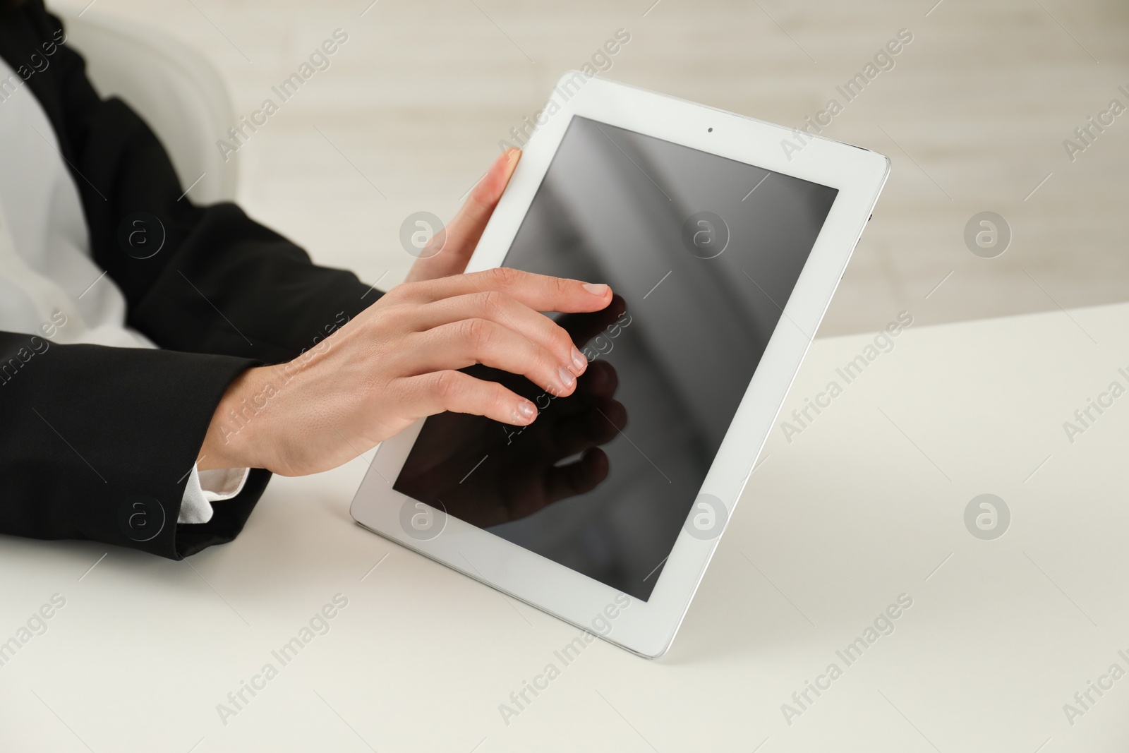 Photo of Businesswoman using tablet at white table indoors, closeup. Modern technology