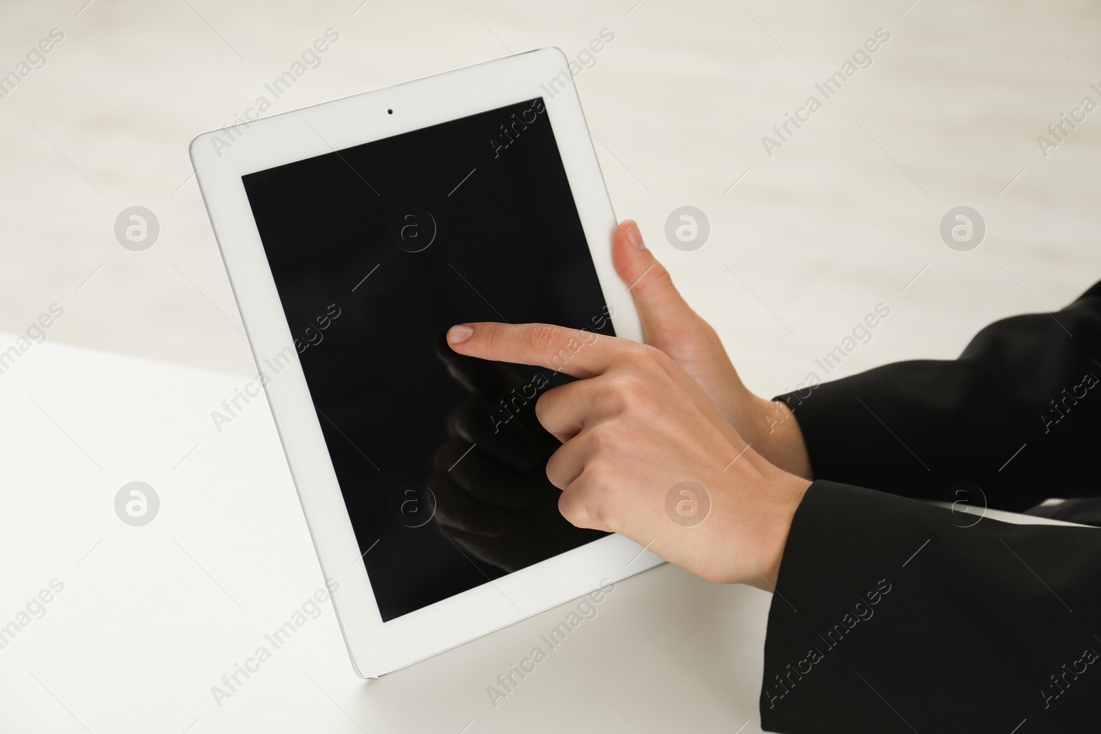 Photo of Businesswoman using tablet at white table indoors, closeup. Modern technology