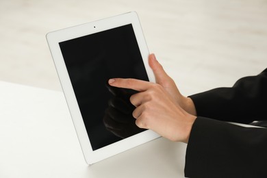 Photo of Businesswoman using tablet at white table indoors, closeup. Modern technology