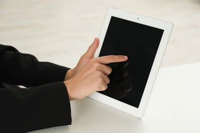 Photo of Businesswoman using tablet at white table indoors, closeup. Modern technology