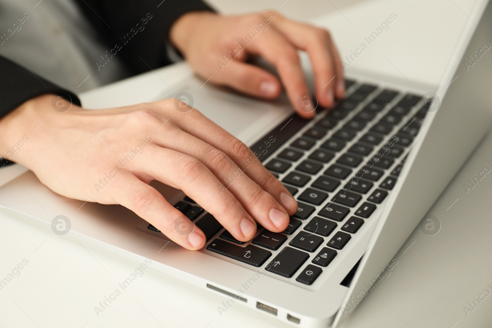 Photo of Businesswoman using laptop at white table indoors, closeup. Modern technology