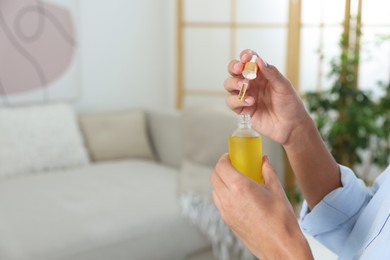 Photo of Young man taking CBD tincture indoors, closeup. Space for text