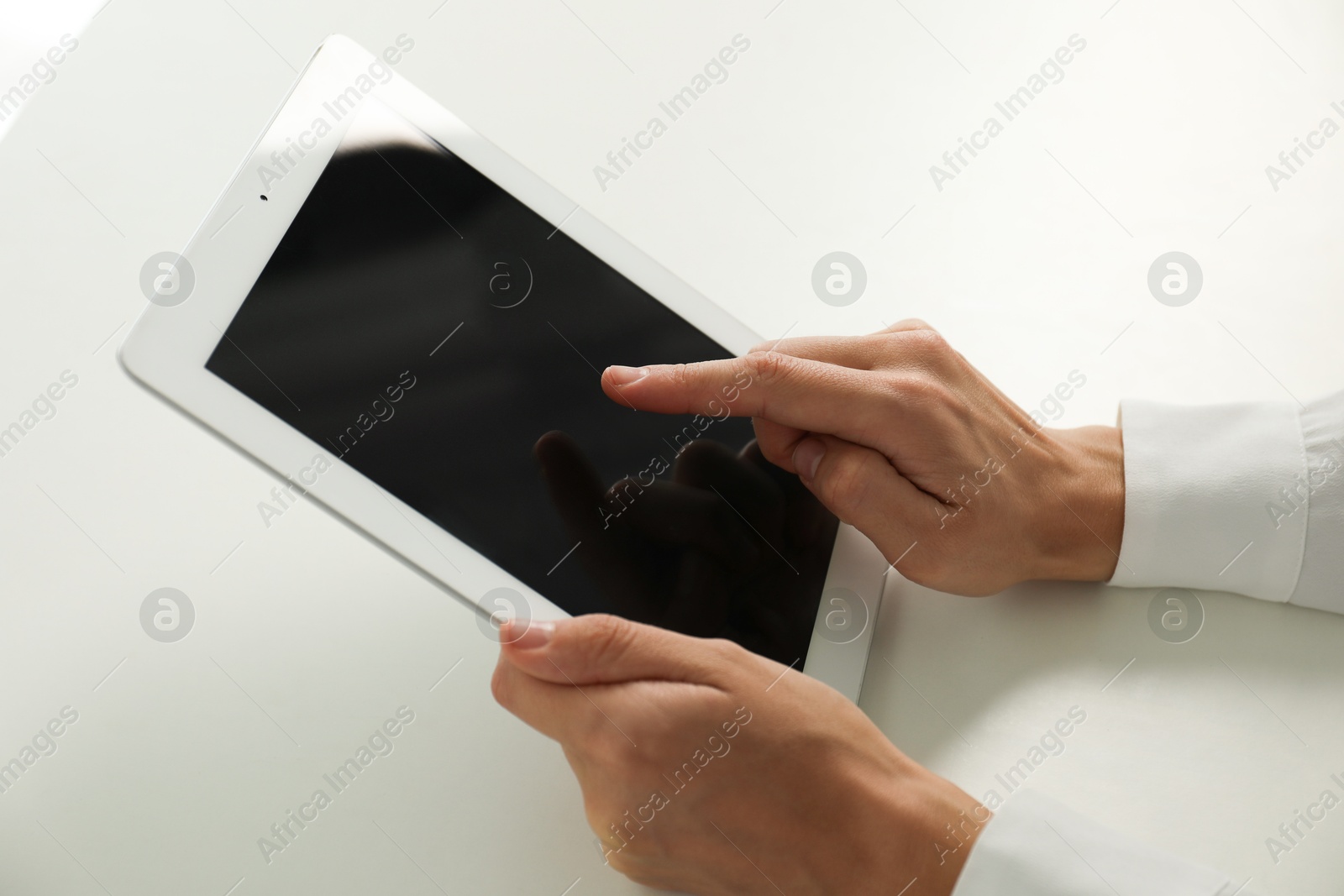 Photo of Businesswoman using tablet at white table indoors, closeup. Modern technology