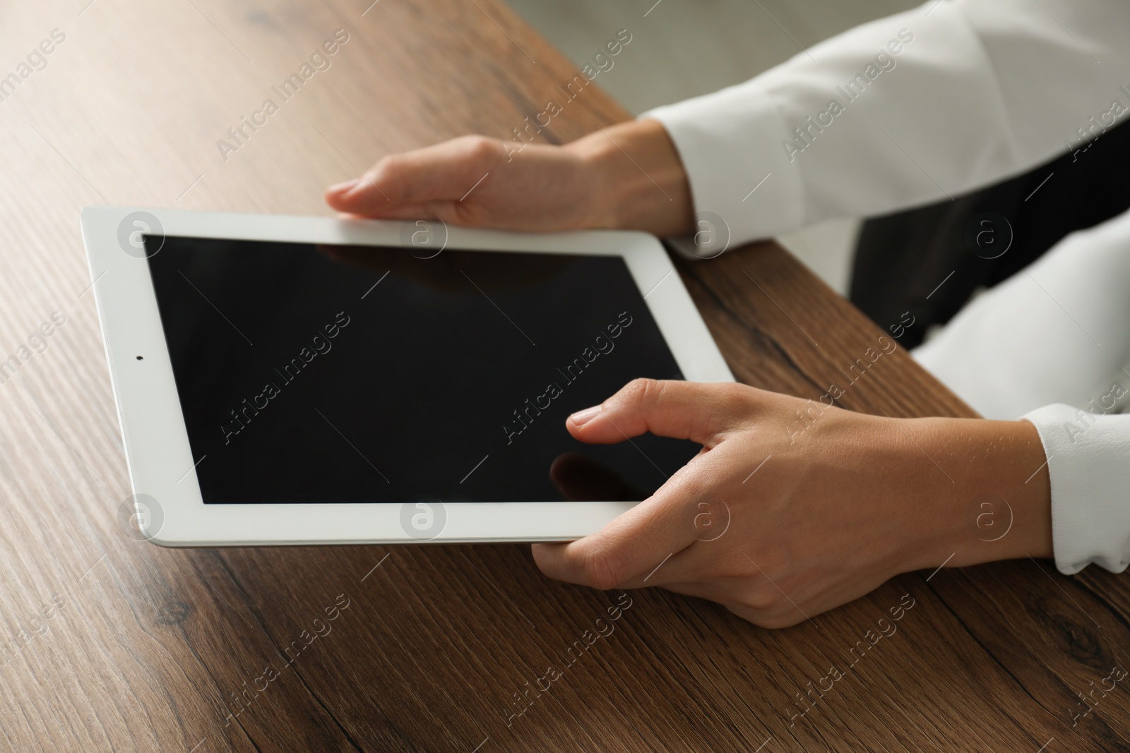 Photo of Businesswoman using tablet at wooden table indoors, closeup. Modern technology