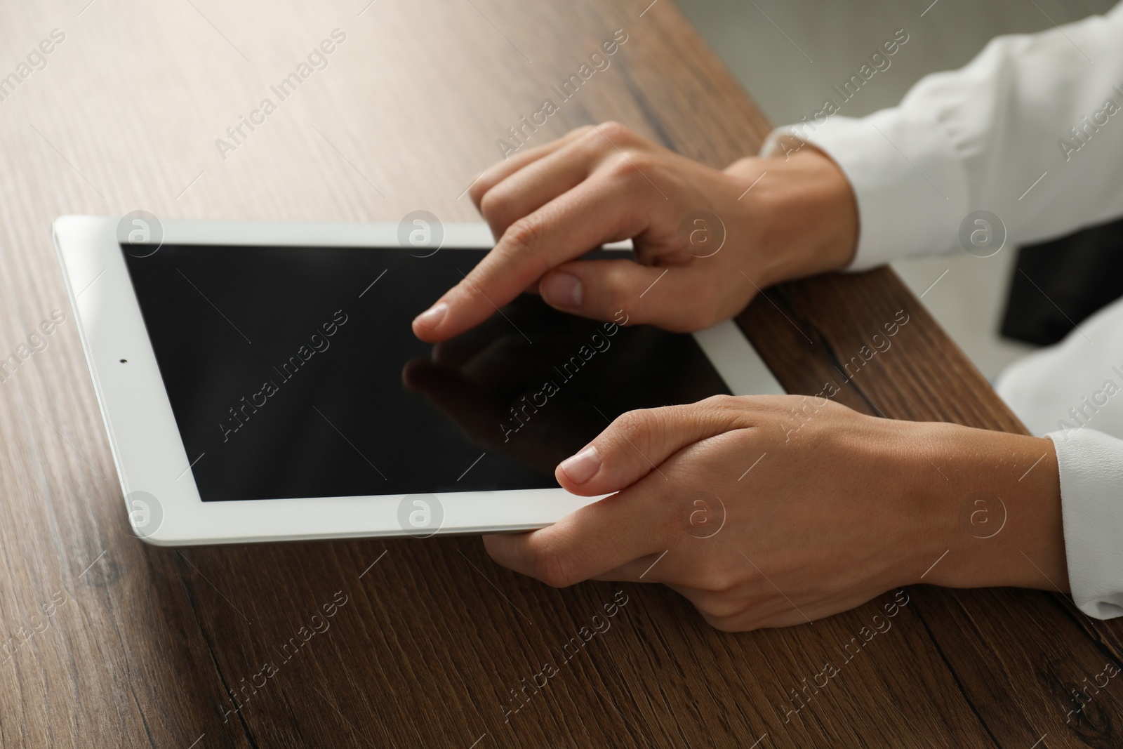 Photo of Businesswoman using tablet at wooden table indoors, closeup. Modern technology