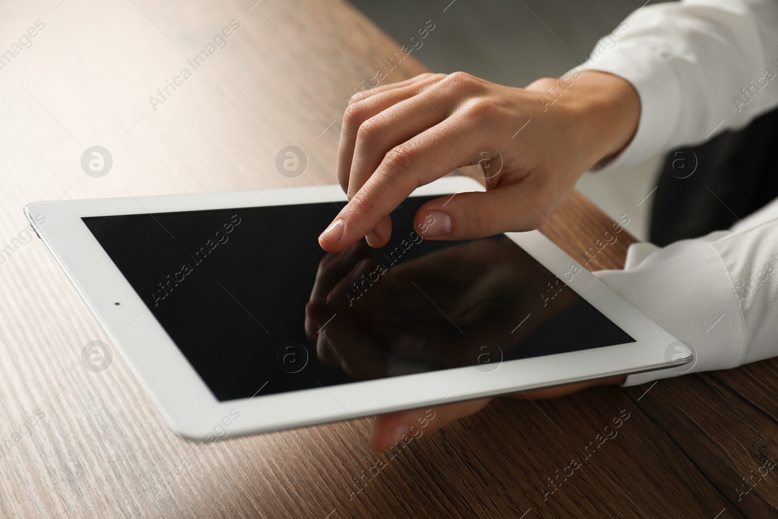 Photo of Businesswoman using tablet at wooden table indoors, closeup. Modern technology