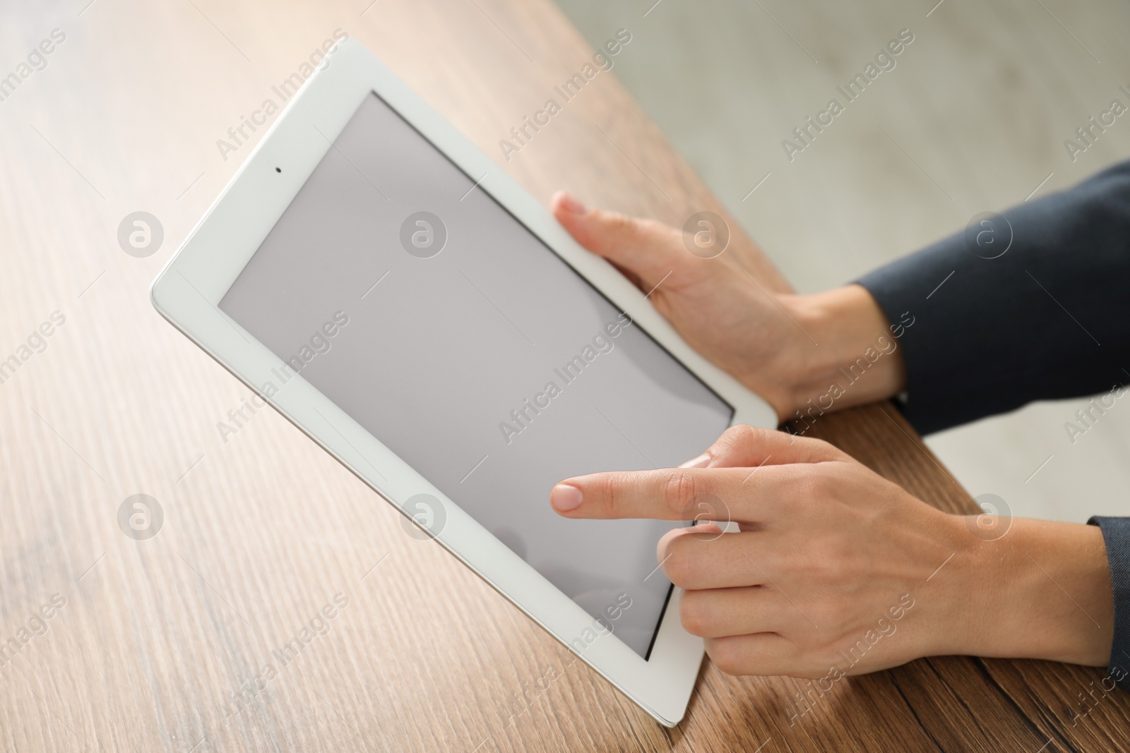 Photo of Businesswoman using tablet at wooden table indoors, closeup. Modern technology