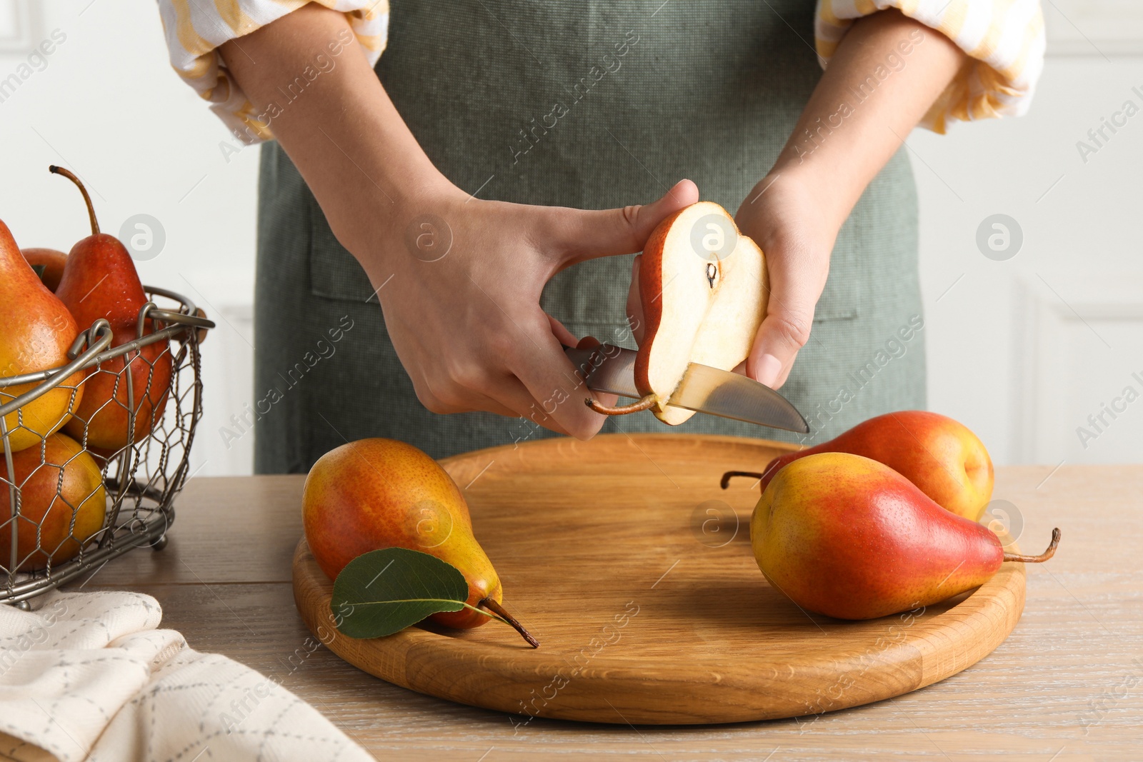 Photo of Woman cutting pear at wooden table, closeup