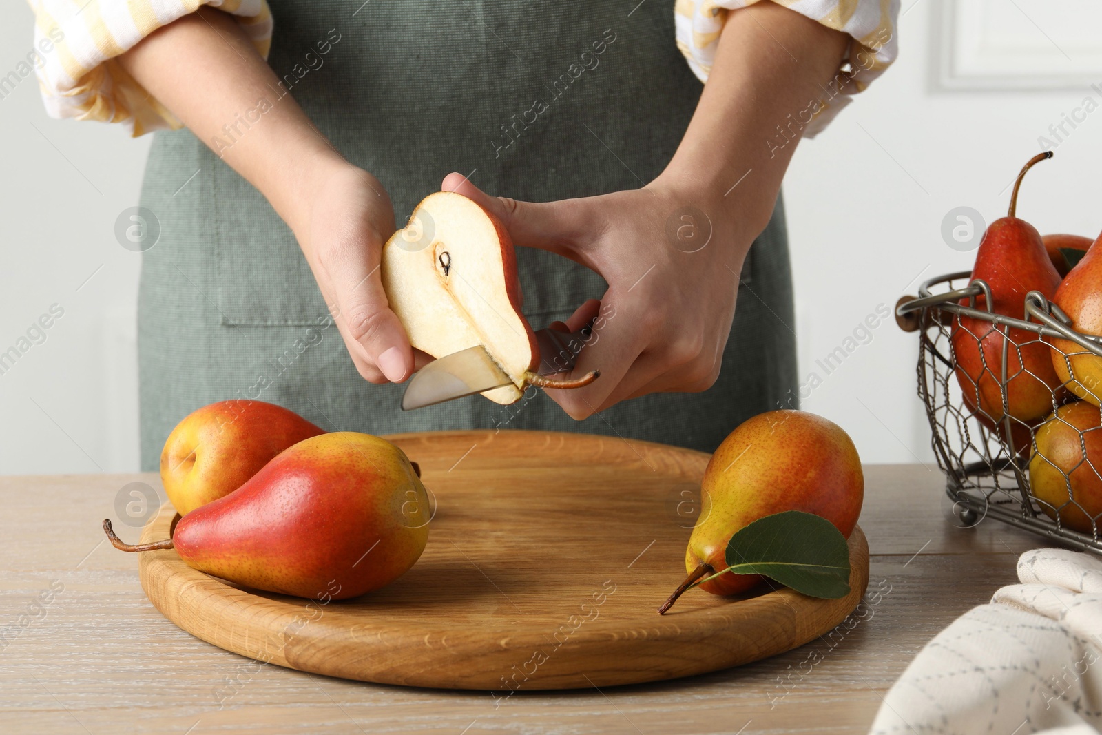 Photo of Woman cutting pear at wooden table, closeup