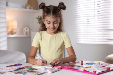 Creating vision board. Girl drawing something with violet marker at light table indoors