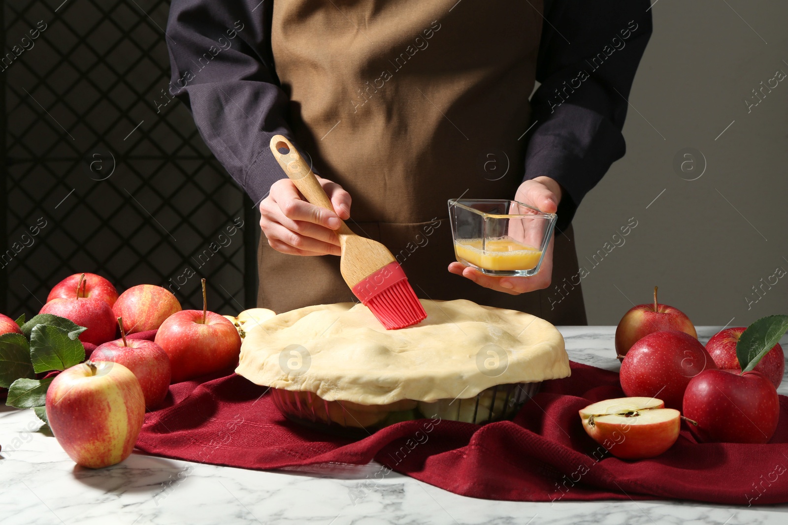 Photo of Woman making homemade apple pie at white marble table, closeup