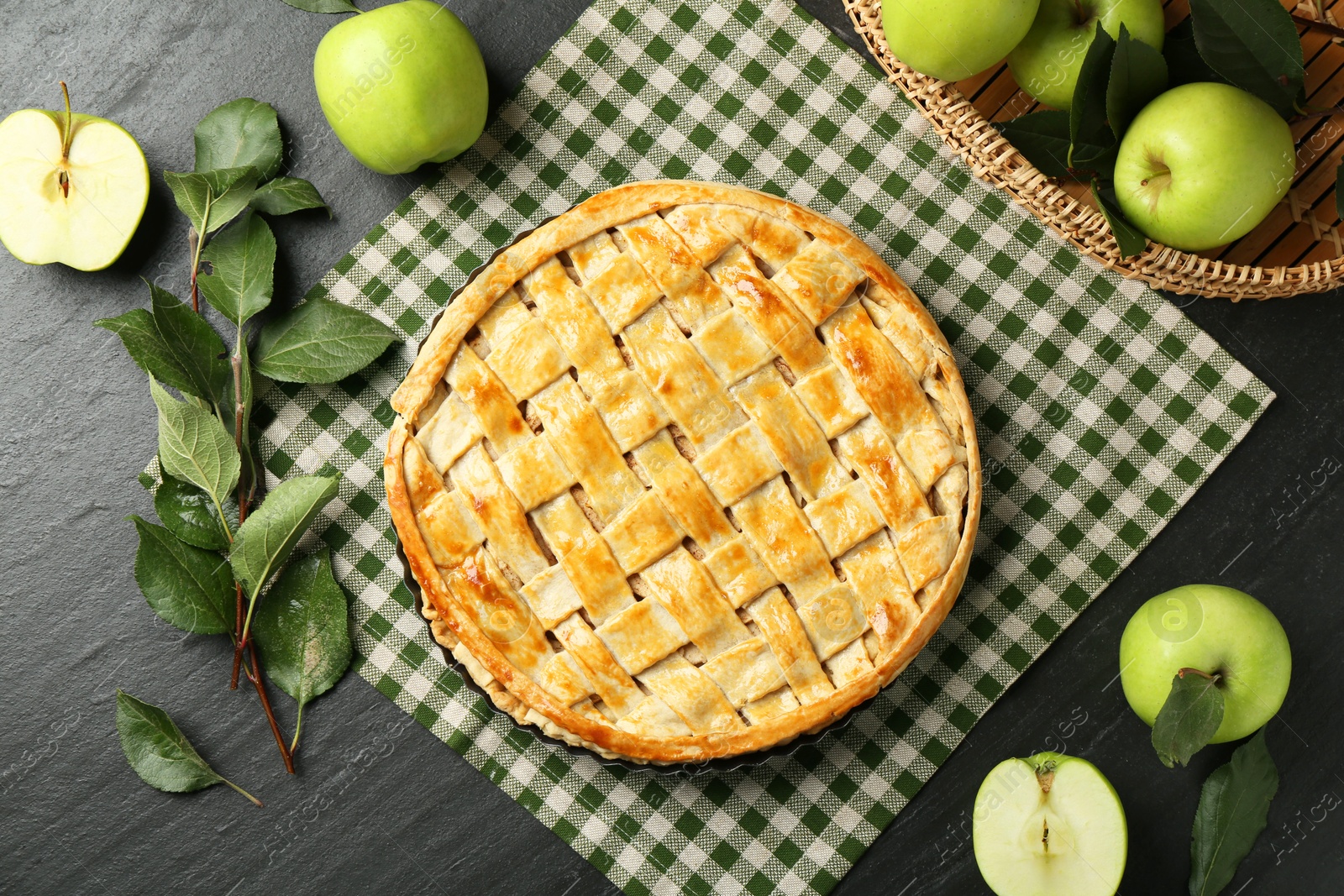 Photo of Flat lay composition with tasty homemade apple pie and ingredients on dark textured table