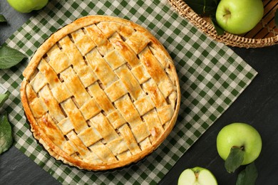 Photo of Flat lay composition with tasty homemade apple pie and ingredients on dark textured table