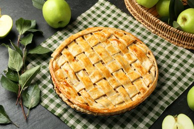 Photo of Tasty homemade pie and apples on dark textured table