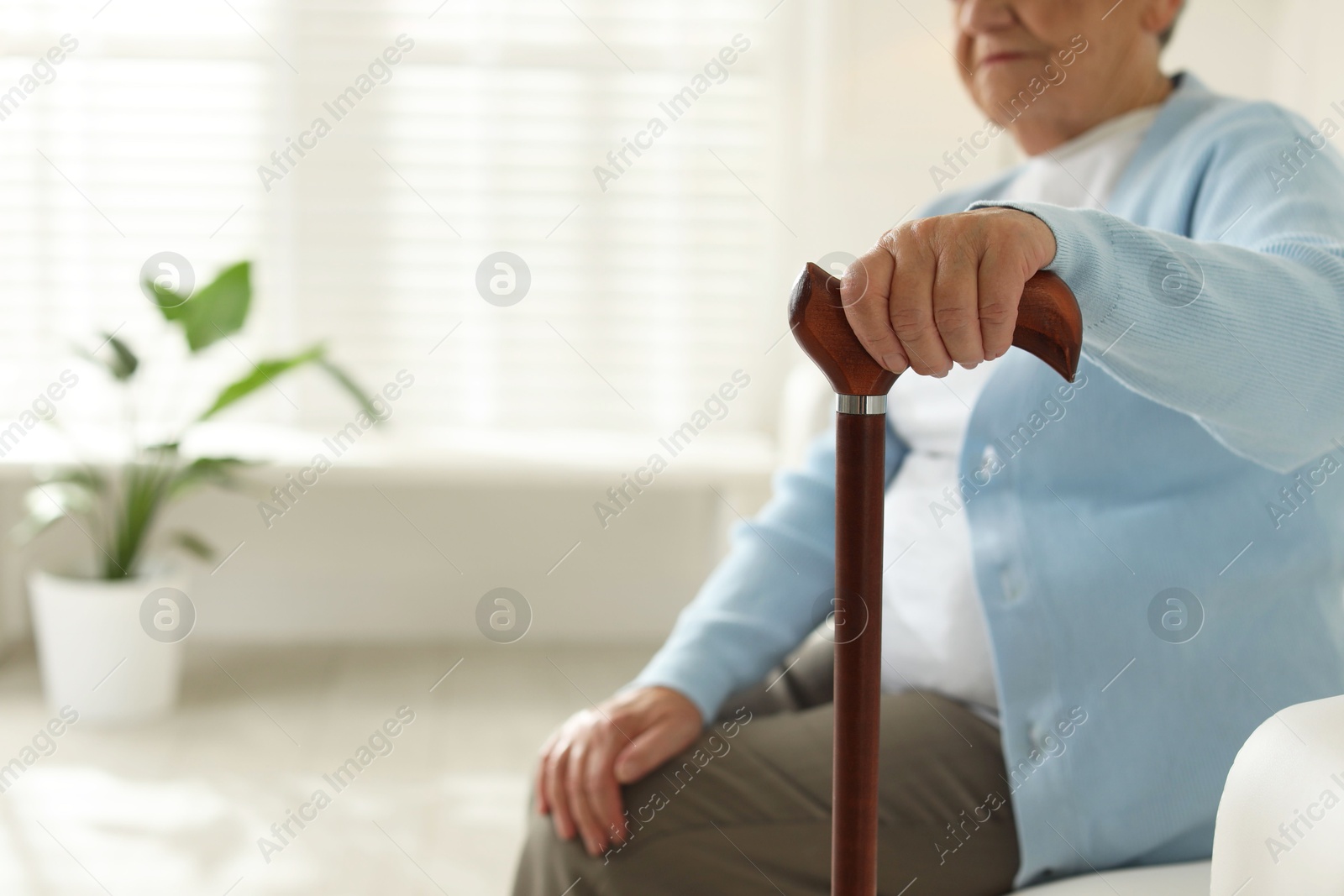 Photo of Lonely senior woman with walking cane indoors, closeup. Space for text