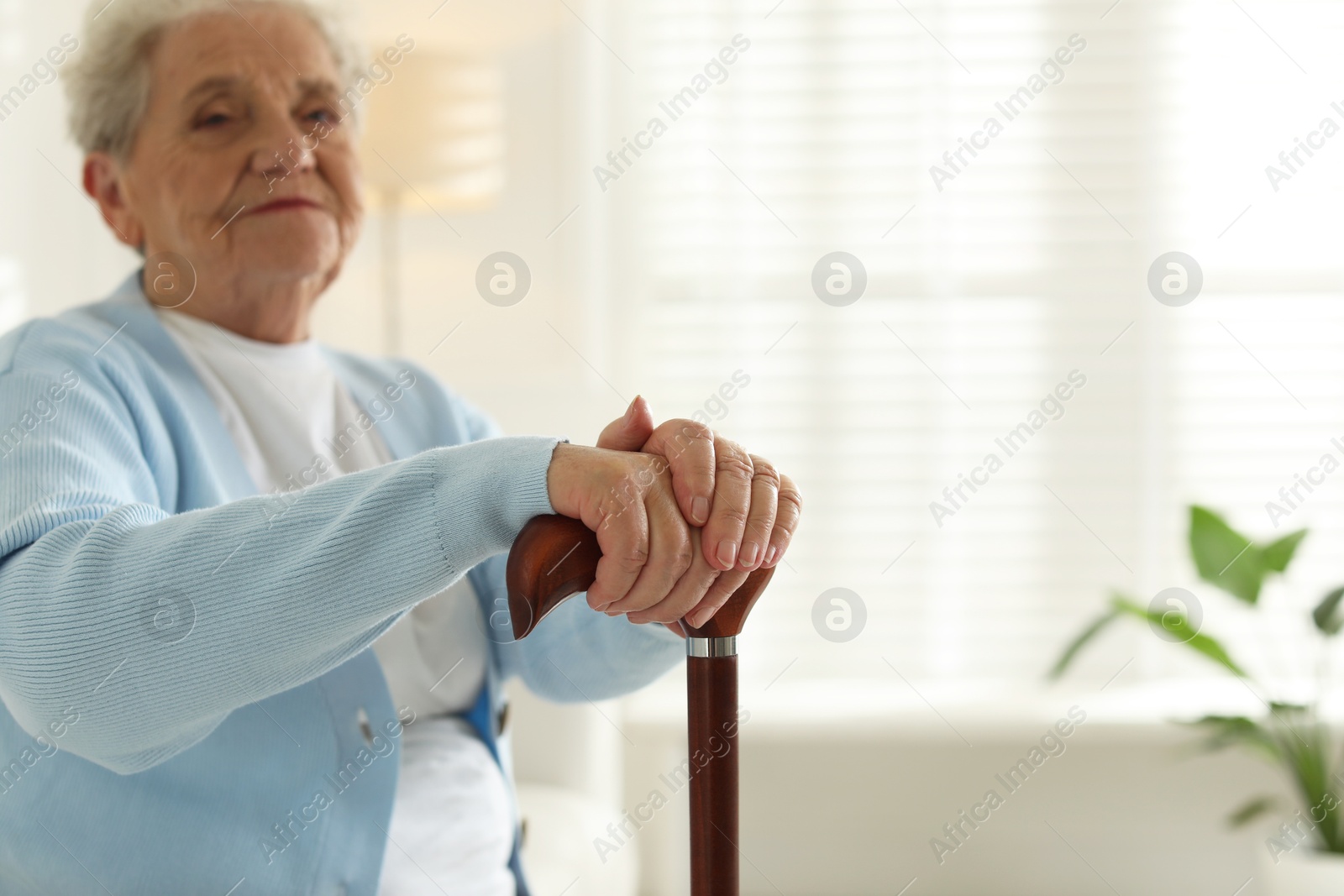 Photo of Lonely senior woman with walking cane indoors, closeup. Space for text