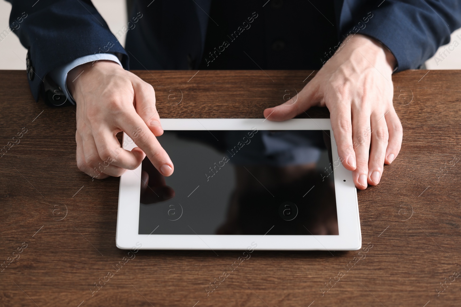 Photo of Businessman using tablet at wooden table, closeup. Modern technology