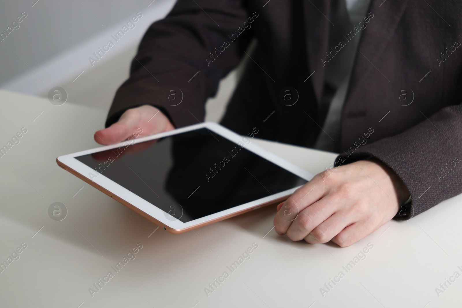 Photo of Businessman using tablet at white table indoors, closeup. Modern technology