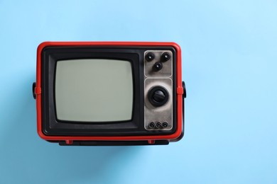 Photo of Retro tv set on light blue background, top view. Space for text