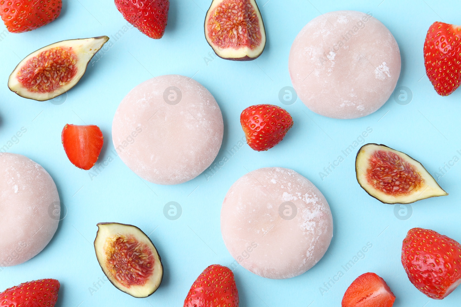 Photo of Delicious mochi, strawberries and figs on light blue background, flat lay