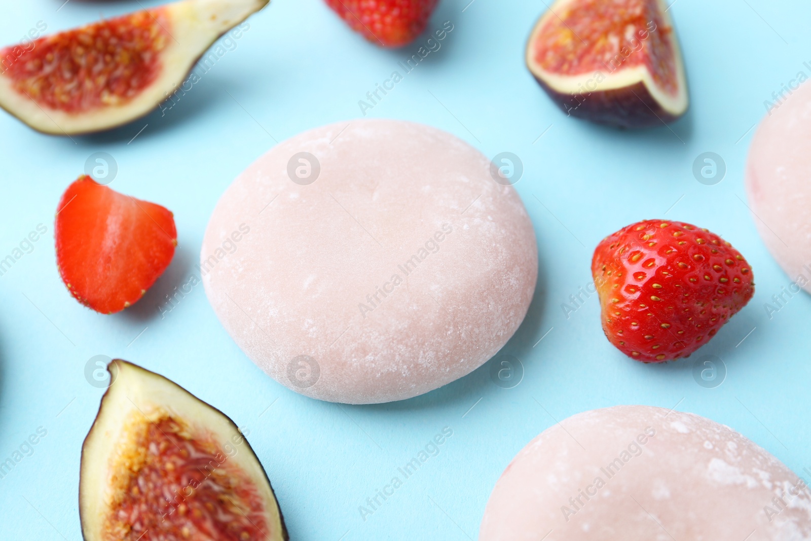 Photo of Delicious mochi, strawberries and figs on light blue background, closeup