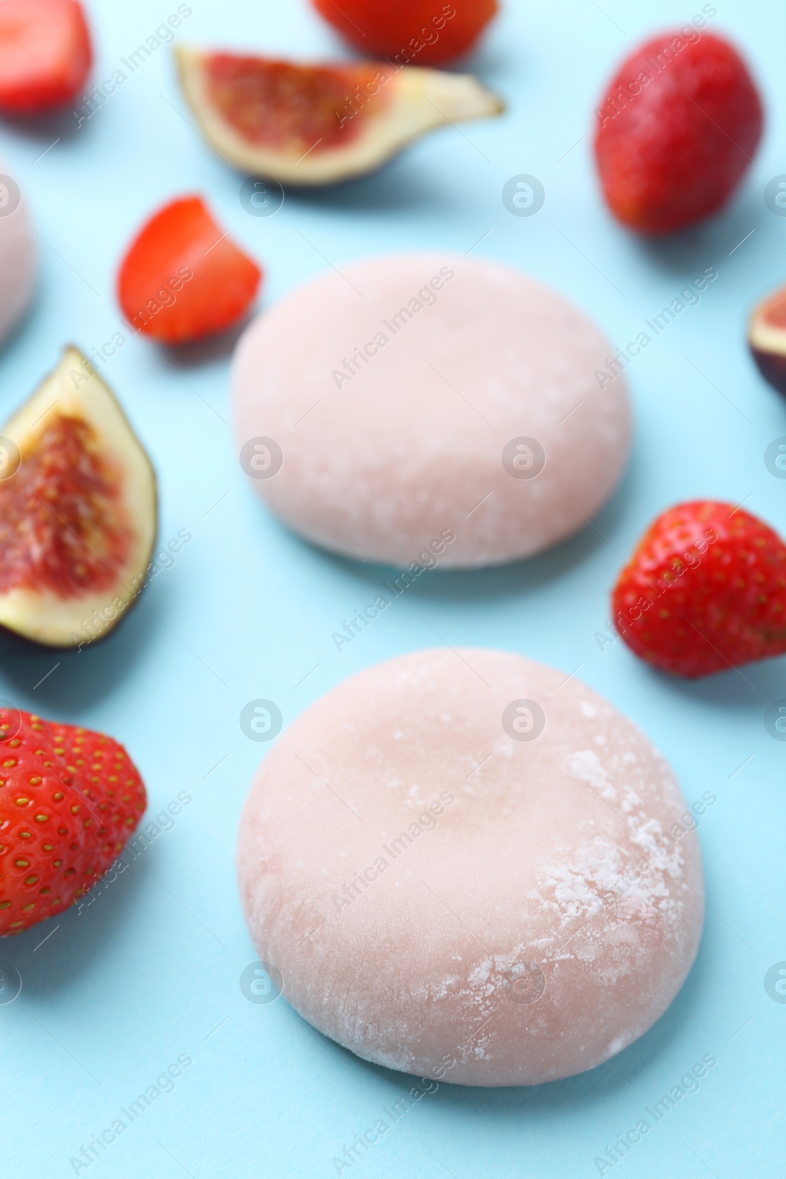 Photo of Delicious mochi, strawberries and figs on light blue background, closeup