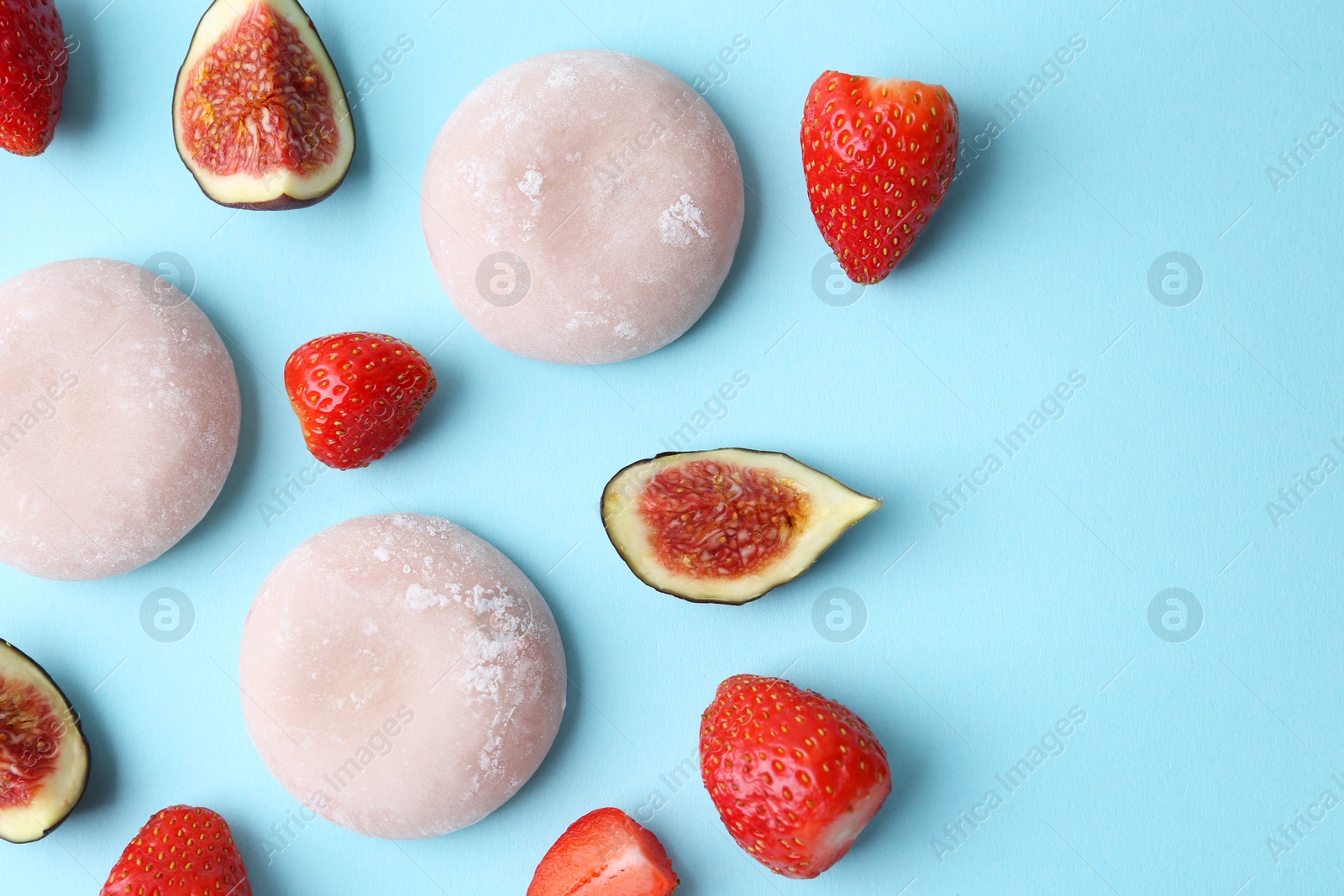 Photo of Delicious mochi, strawberries and figs on light blue background, flat lay