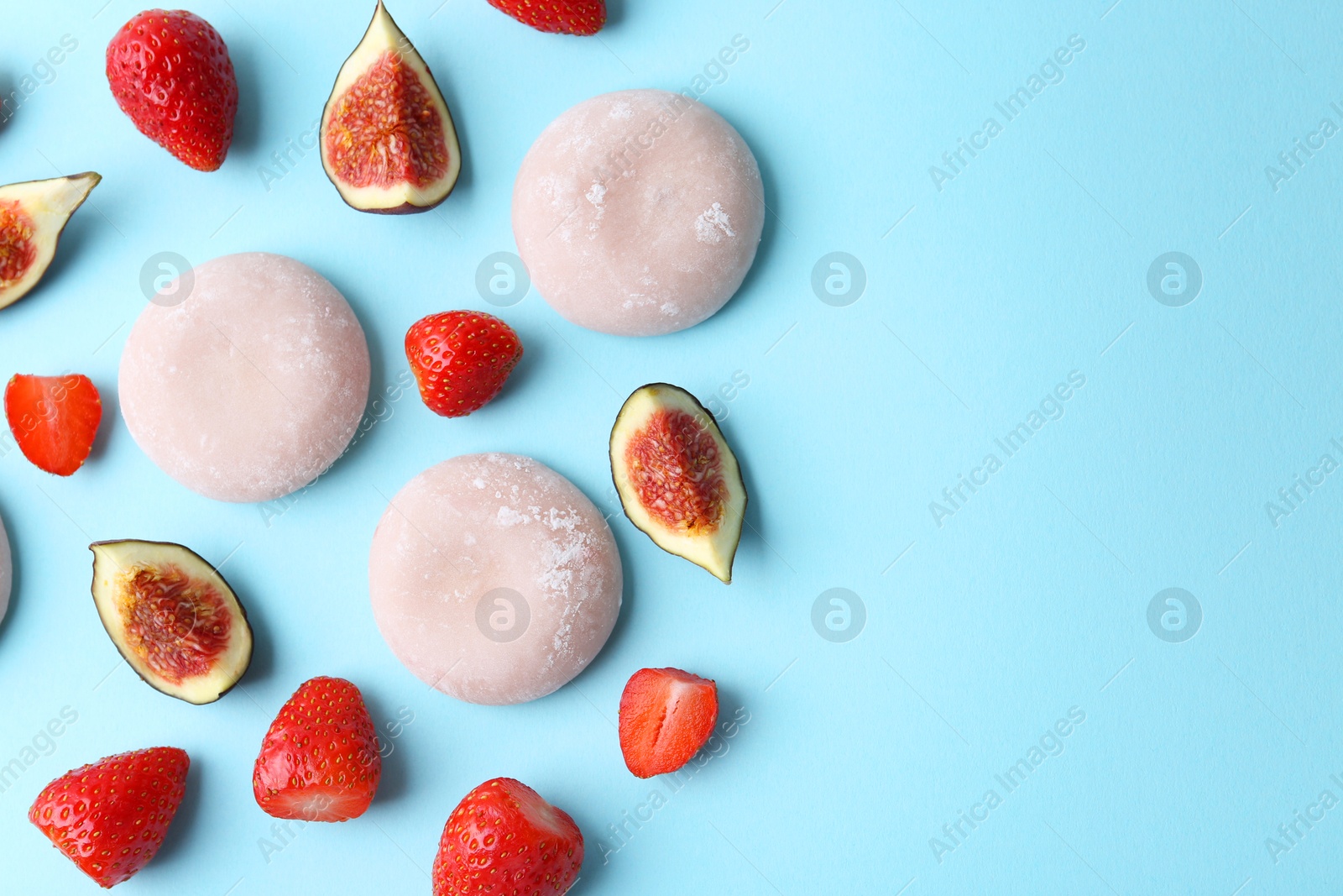 Photo of Delicious mochi, strawberries and figs on light blue background, flat lay. Space for text