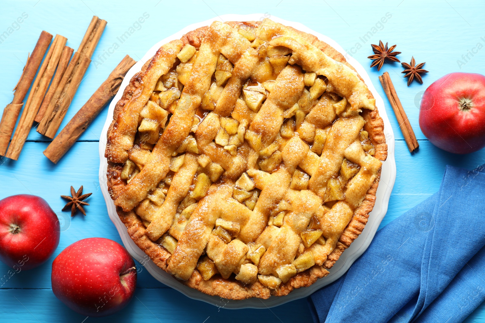 Photo of Homemade apple pie and ingredients on light blue wooden table, flat lay