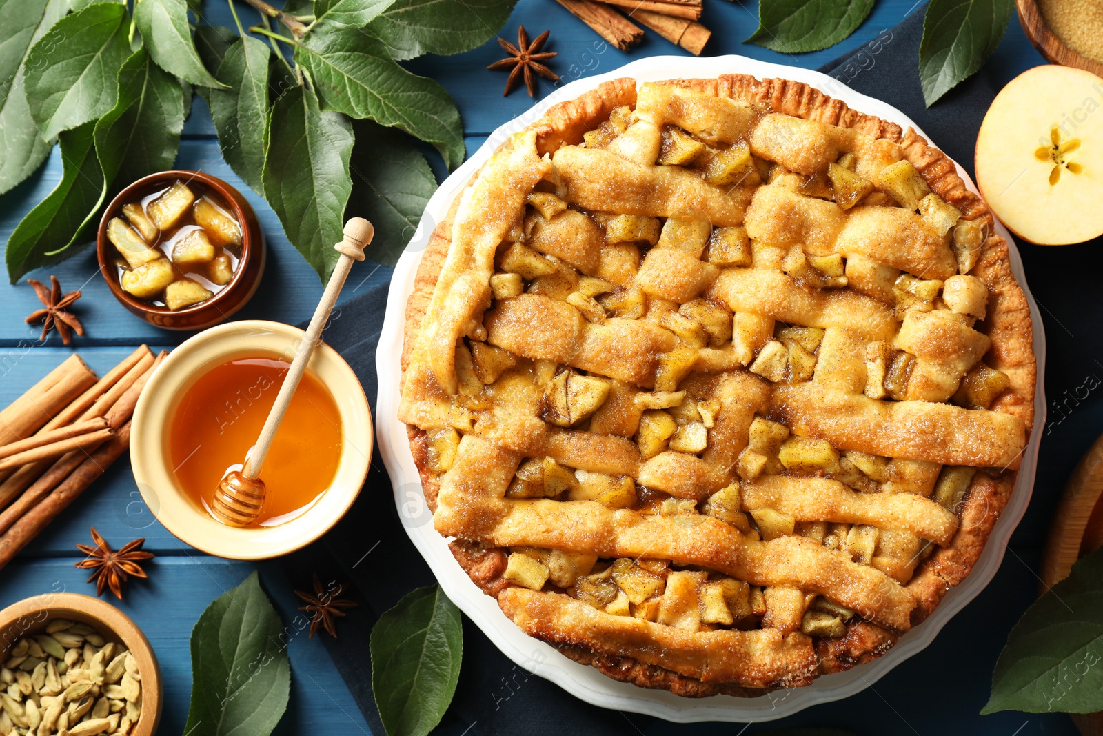 Photo of Homemade apple pie and ingredients on blue wooden table, flat lay