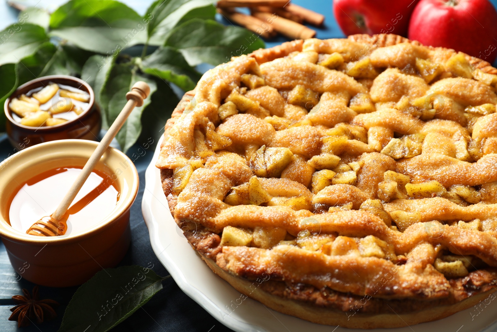 Photo of Homemade apple pie and ingredients on blue wooden table, closeup