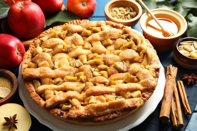 Photo of Homemade apple pie and ingredients on blue wooden table