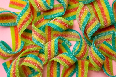 Photo of Tasty rainbow sour belts on pink background, top view