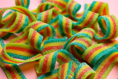 Photo of Tasty rainbow sour belts on pink background, closeup