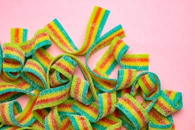 Photo of Tasty rainbow sour belts on pink background, top view