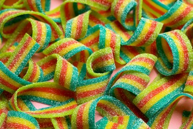 Photo of Tasty rainbow sour belts on pink background, closeup