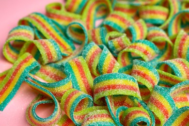 Photo of Tasty rainbow sour belts on pink background, closeup