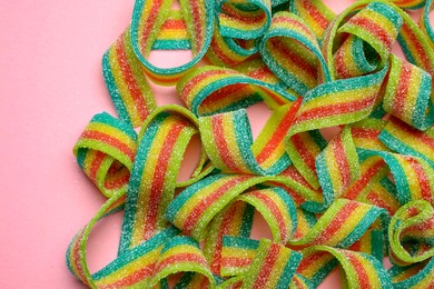 Photo of Tasty rainbow sour belts on pink background, top view