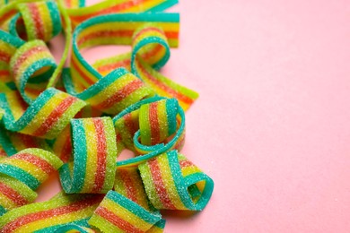 Photo of Tasty rainbow sour belts on pink background, closeup. Space for text