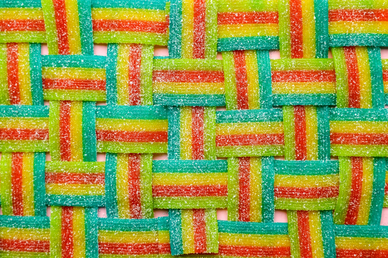 Photo of Tasty rainbow sour belts on pink background, top view